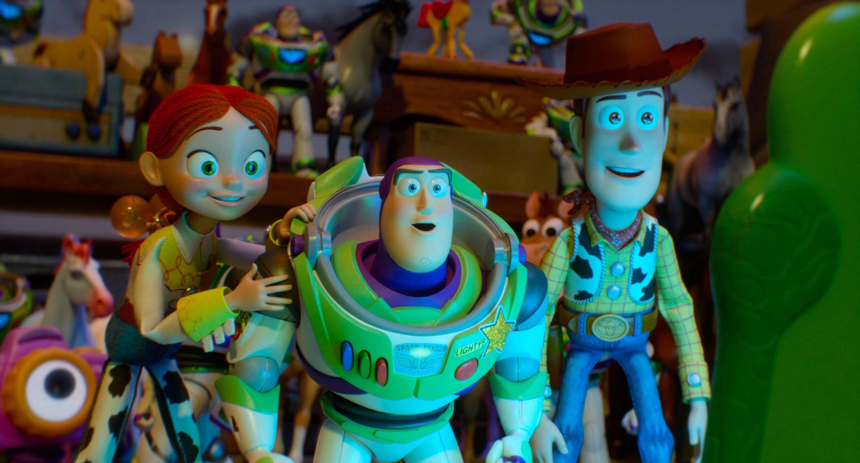 Three toy figures—a red-haired girl, a space-suited astronaut, and a cowboy—stand together among other toys on a shelf, gazing toward a green dinosaur on the right.