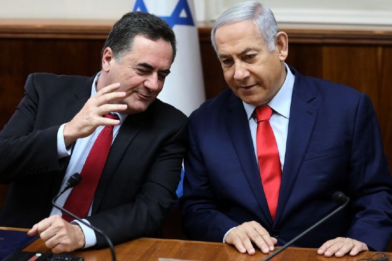 Five officials sit at a table labeled "ISRAEL," "UNITED STATES," and "LEBANON," backed by American, Israeli, and Lebanese flags and a marble statue.