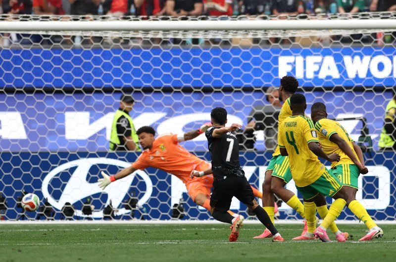 A soccer player wearing a white jersey with the number 8 raises both arms in celebration, with a scoreboard graphic showing Canada 0, Morocco 3.