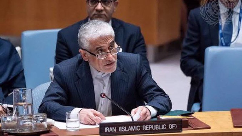 A gray-haired man in glasses and a dark suit speaks into a microphone at a desk labeled "IRAN (ISLAMIC REPUBLIC OF)" with a UN emblem visible.