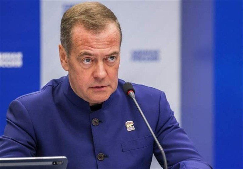 A man in a dark suit and red tie sits at a desk in front of a Russian flag, with overlaid text reading "PUTIN SAYS RUSSIA IS GOING THROUGH 'DIFFICULT PERIOD' AMID UKRAINE WAR, VOWS TO OVERCOME CHALLENGES."