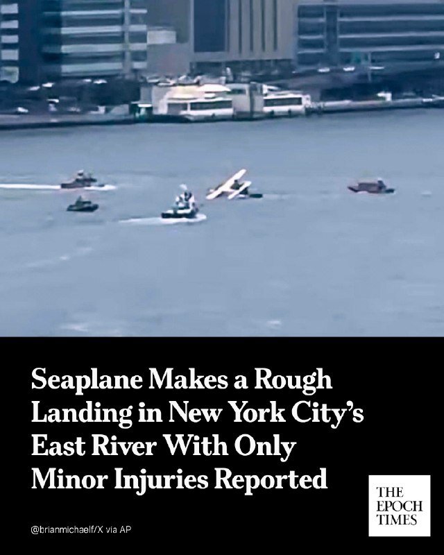 A seaplane sits partially tilted on a river's surface near several boats, with city buildings visible along the shoreline in the background.