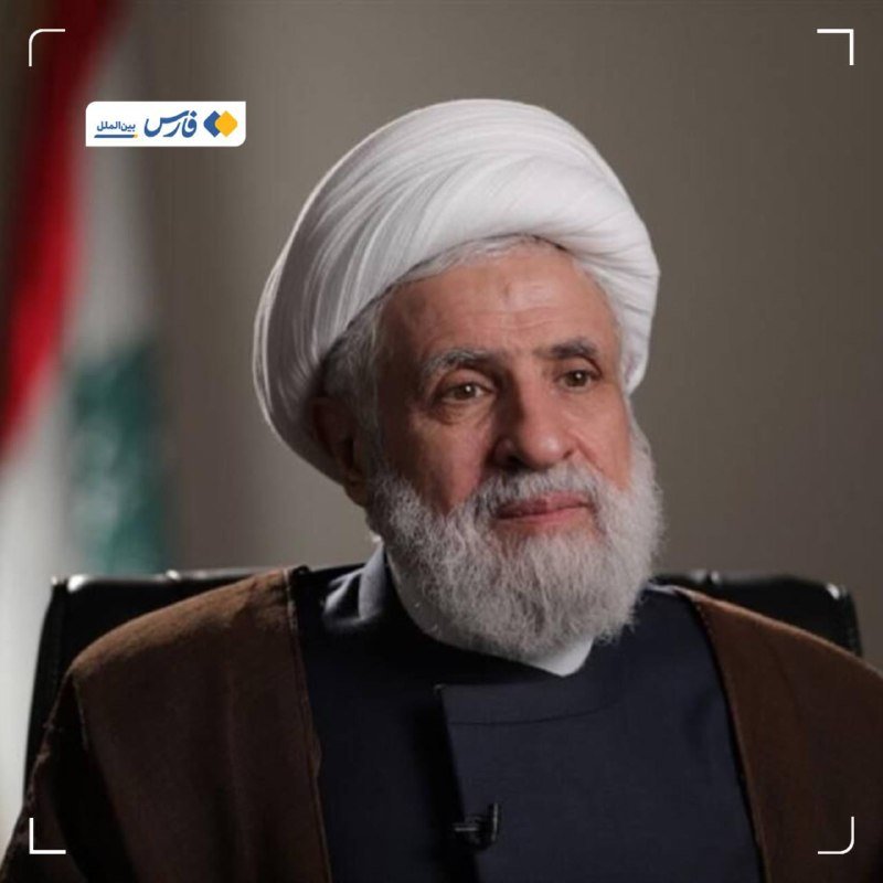 A bearded cleric in a white turban and dark robe appears in a televised interview setting.