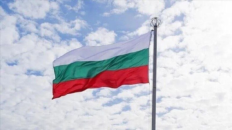 A white, green, and red horizontal tricolor flag waves on a metal flagpole against a blue sky filled with scattered white clouds.