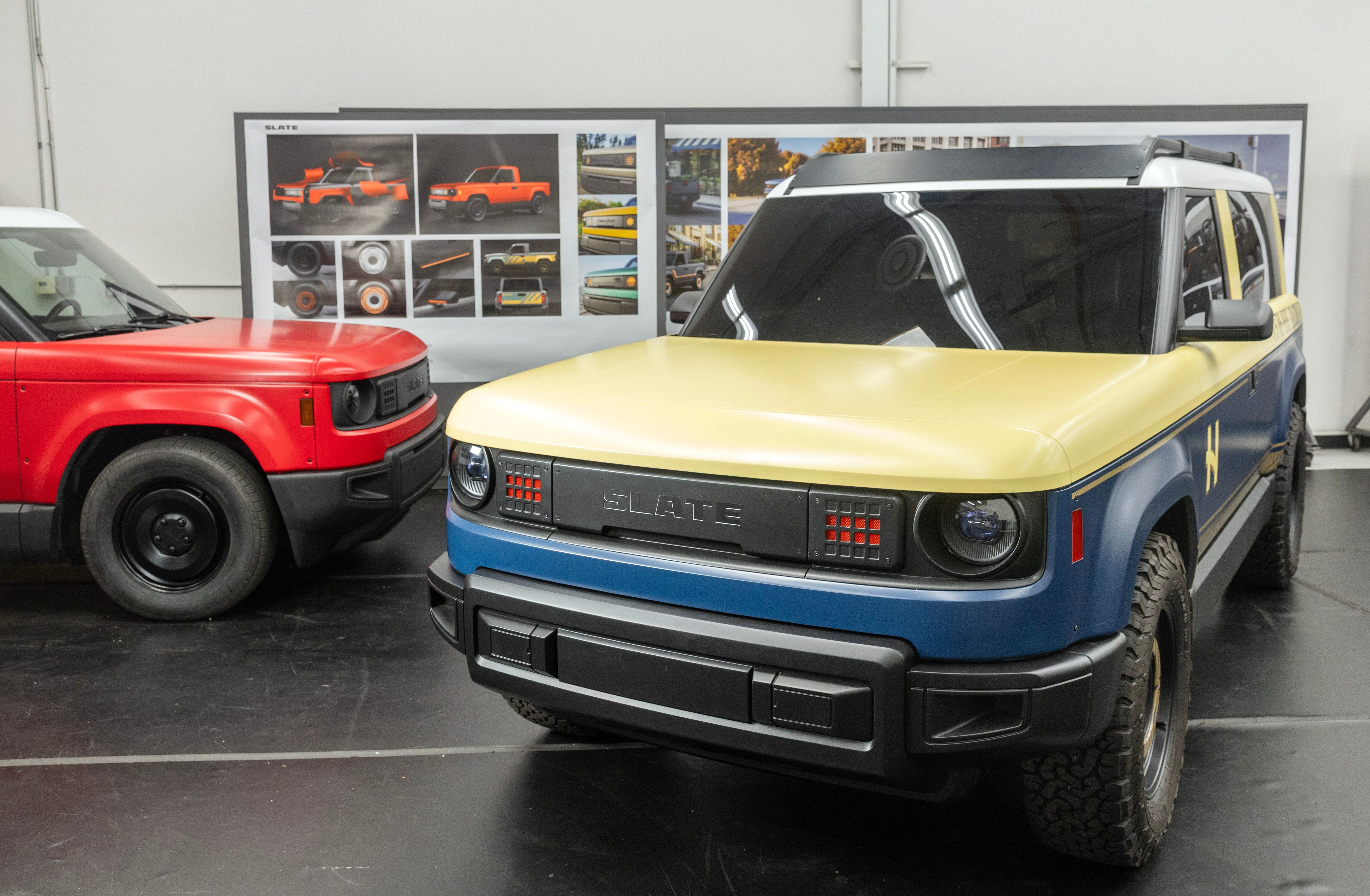 Two Slate-branded pickup trucks—one red, one blue and gold—display in a showroom alongside design renderings of the vehicle.