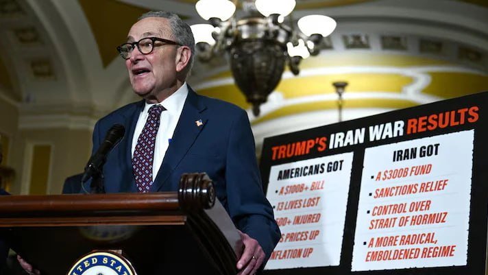 A man in a dark suit and glasses speaks at a podium beside a sign reading "TRUMP'S IRAN WAR RESULTS."