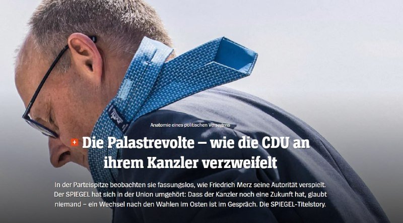 A man in glasses and suit looks down with a blue tie blowing backward over his shoulder, accompanied by German text about a "Palastrevolte" and CDU chancellor.