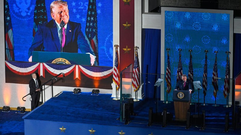 Two men in dark suits shake hands in front of an American flag and two Ukrainian flags during a formal meeting.