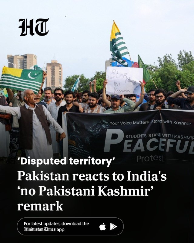 A crowd of people holds a banner reading "PEACEFUL" and others wave flags while gathered outdoors in a protest.