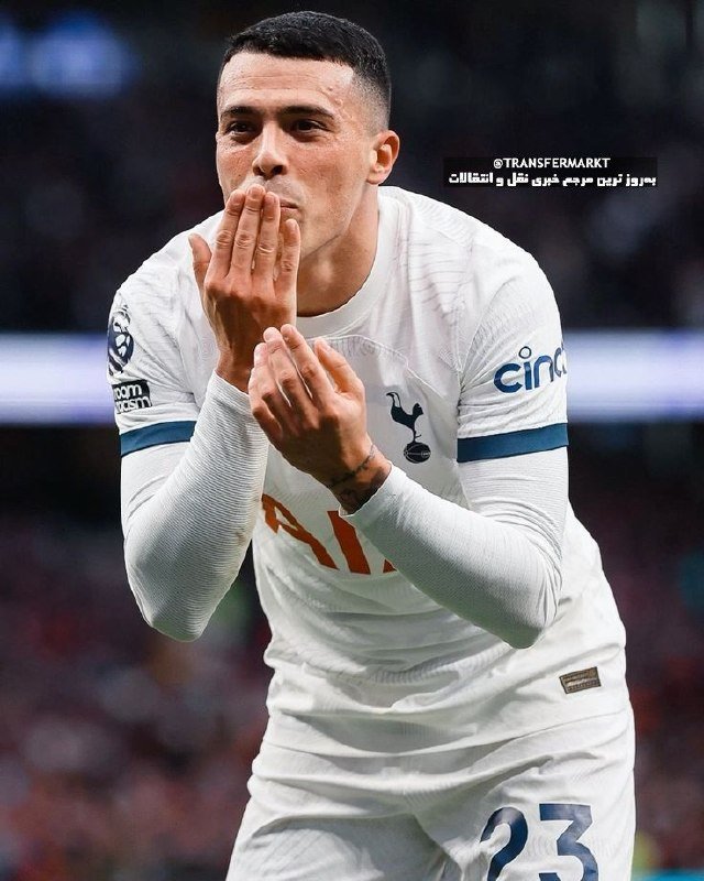 A male soccer player in a white Tottenham Hotspur jersey with the number 23 claps his hands in celebration on the pitch.