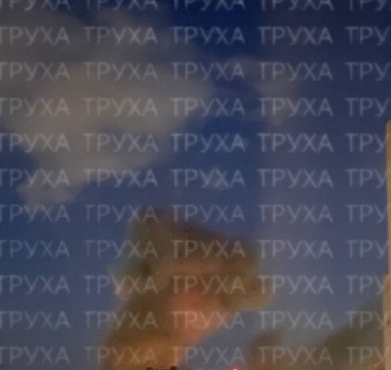 The image is overlaid with repeating "INFO Київ" text and Telegram channel watermarks, obscuring a blurry background showing a dark plume of smoke rising near a building.