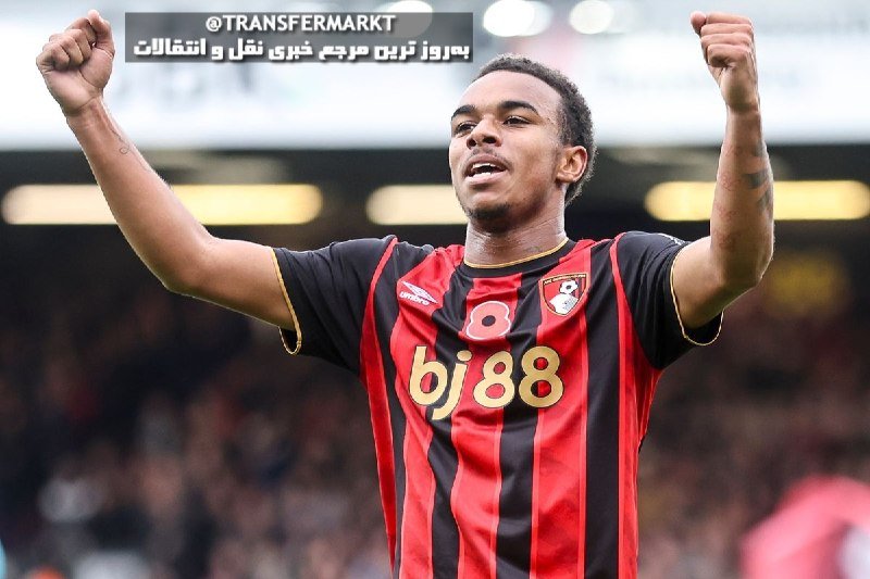 A soccer player in a red and black striped jersey with "bj88" sponsorship raises both arms with clenched fists in celebration inside a stadium.