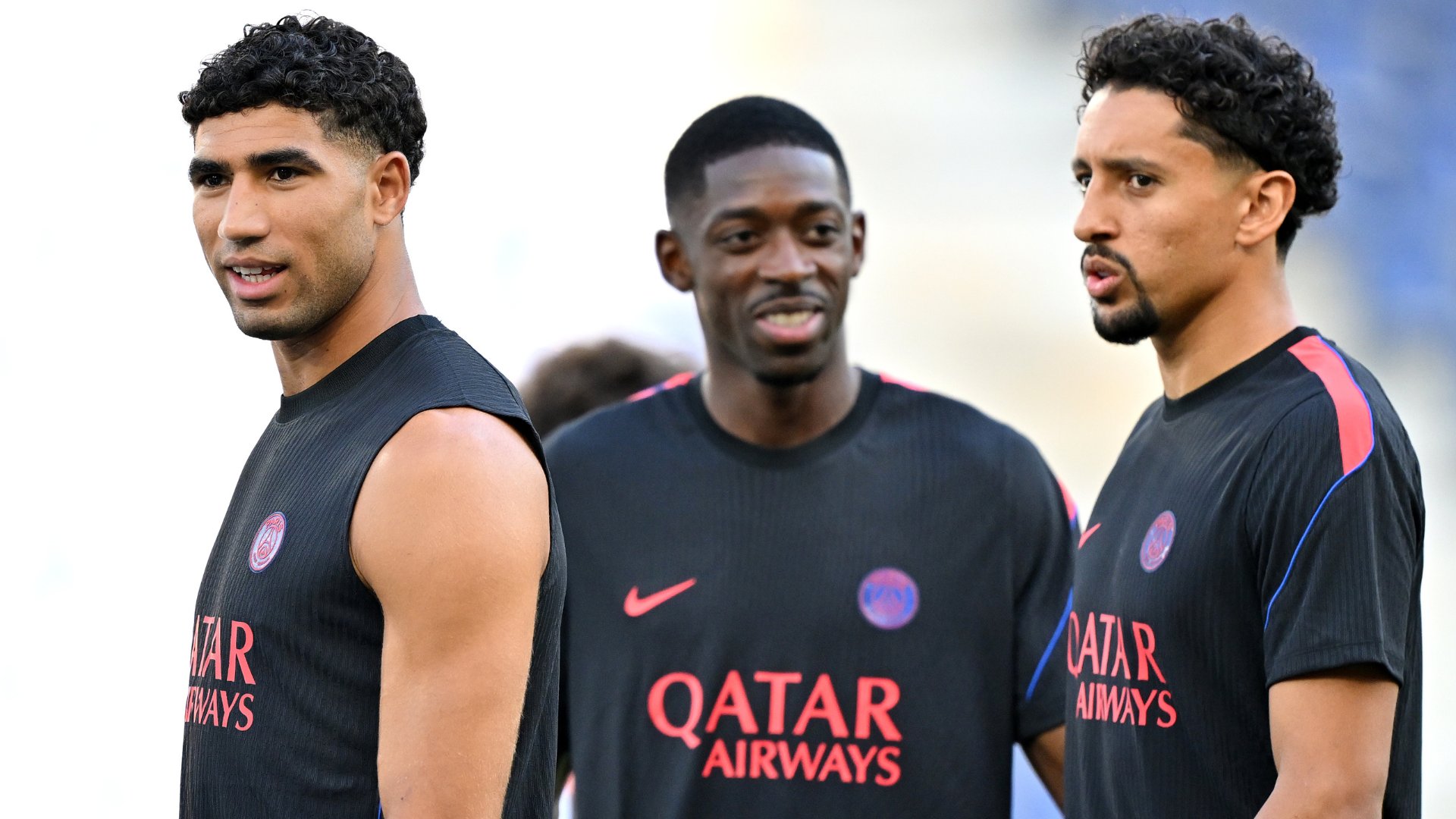 Three men wearing black and pink Nike athletic shirts with "QATAR AIRWAYS" printed across the front stand together in an outdoor setting.