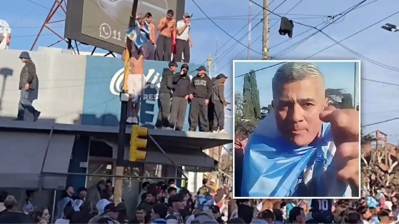 A crowd gathers beneath a building where shirtless fans in dark clothing stand on a ledge draped in light blue flags, with an inset portrait of a mustached man pointing toward the camera.