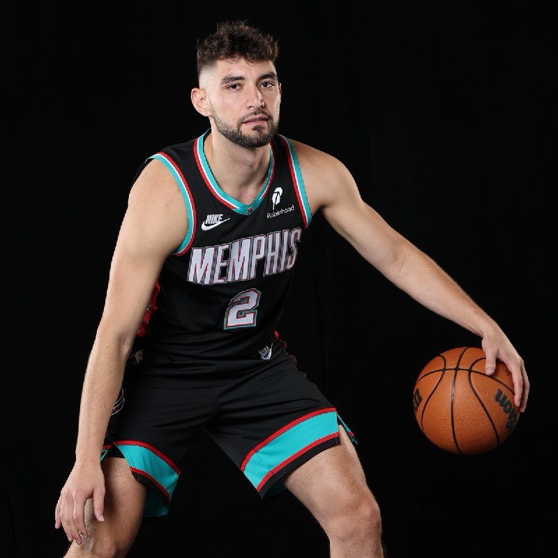 A bearded basketball player wearing a black Memphis jersey numbered 2 poses with a Wilson basketball against a black backdrop.