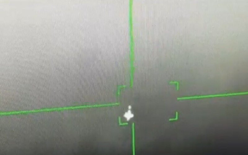 A green targeting reticle overlays a hazy gray screen, centering on a small bright object.