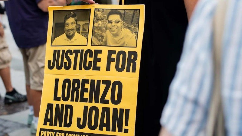 A person holds a yellow protest sign reading "JUSTICE FOR LORENZO AND JOAN!" featuring two black-and-white photos of smiling men.