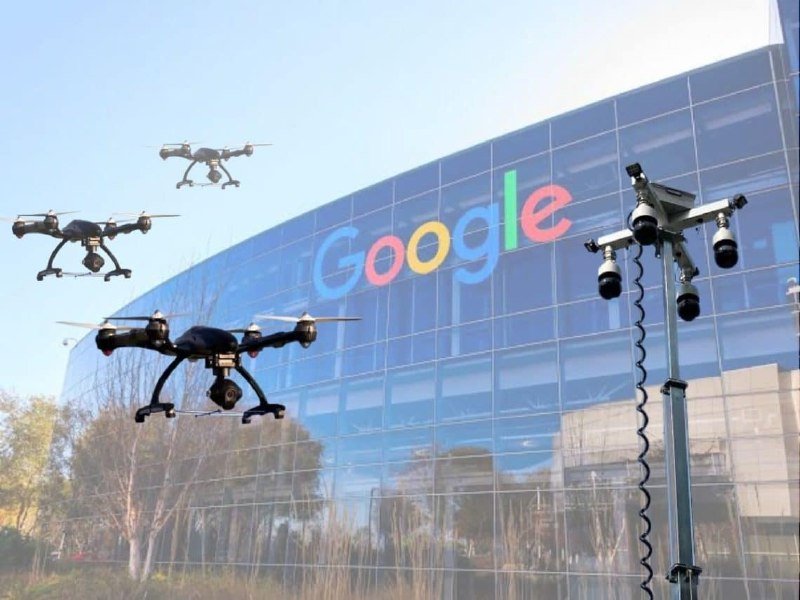 Three drones fly outside a glass building displaying the "Google" logo, alongside surveillance cameras mounted on a pole.