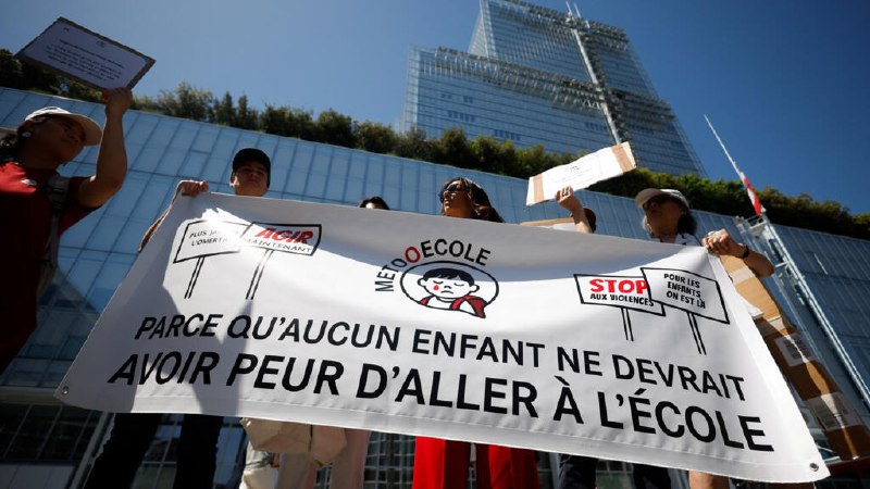 A dark, angular aircraft model is displayed on a platform at an outdoor exhibition, with banners reading "Airbus" and "Dassault Aviation" and a Falcon jet visible in the background.