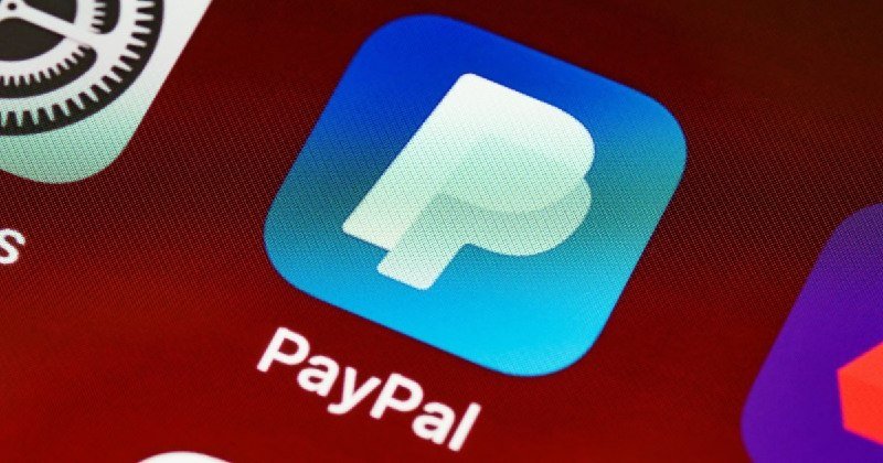 Close-up photograph of a smartphone screen displaying the PayPal app icon alongside portions of other app icons.
