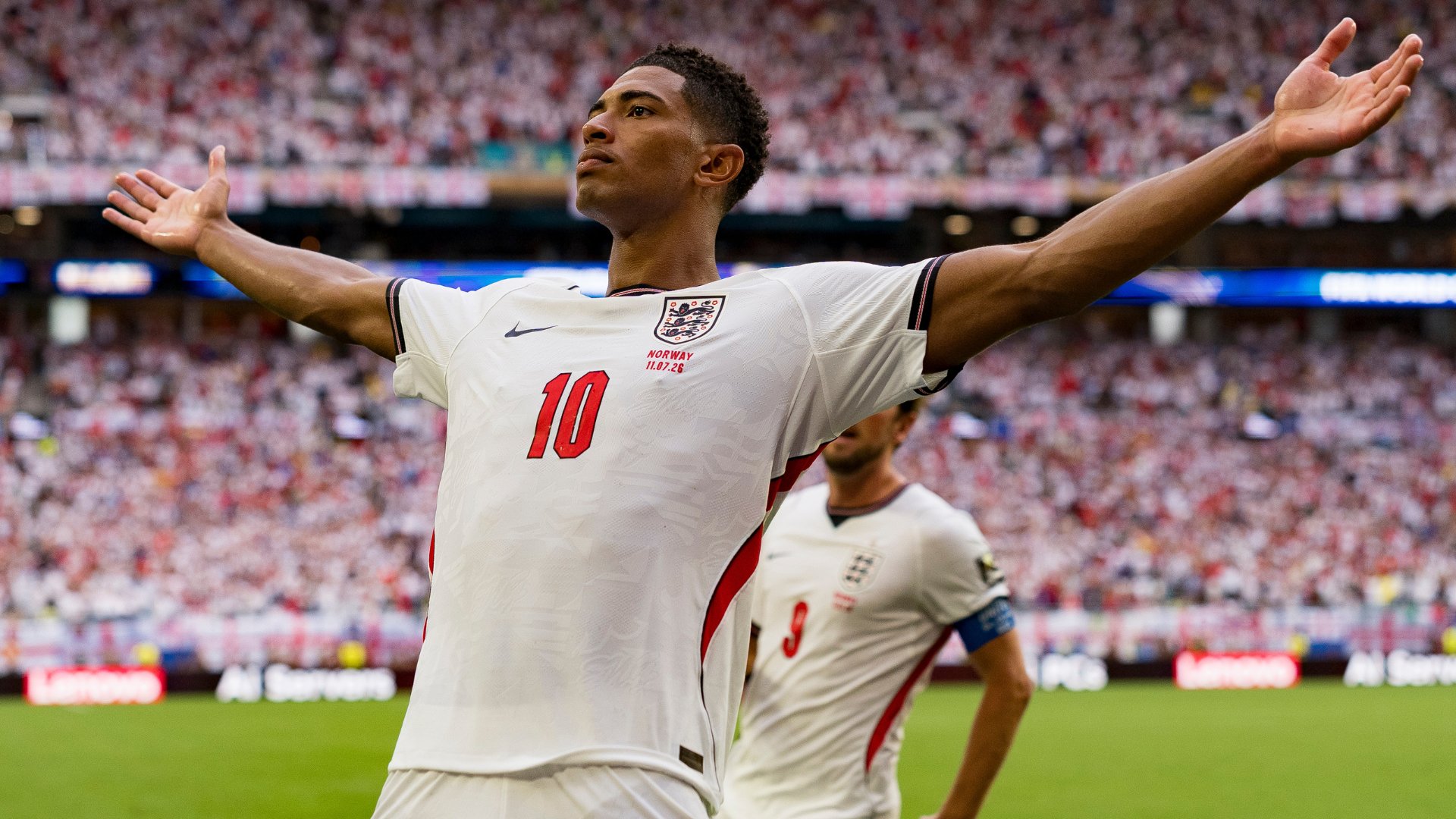 England player wearing the number 10 jersey raises both arms in celebration during a match in a packed stadium.