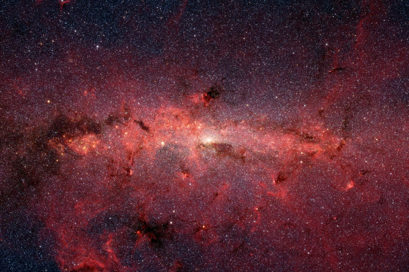 An astronomical image showing a bright central region of a galaxy with a horizontal band of glowing pink and red nebulae scattered across a dark, star-filled sky.