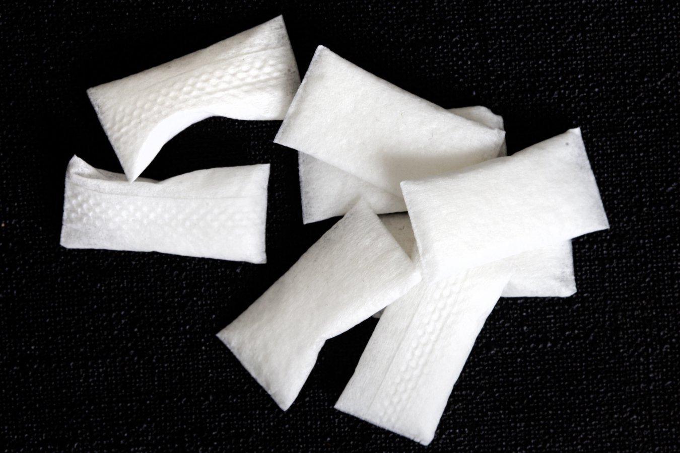 A pile of torn white paper strips rests on a dark textured fabric surface.
