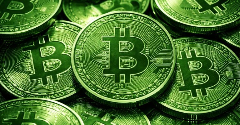 A pile of green Bitcoin tokens featuring the "B" logo and "DECENTRALIZED PEER TO PEER" inscriptions overlap in close-up view.