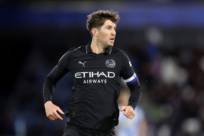 A soccer player in a dark Manchester City jersey with "Etihad Airways" sponsor runs on the field during a match.