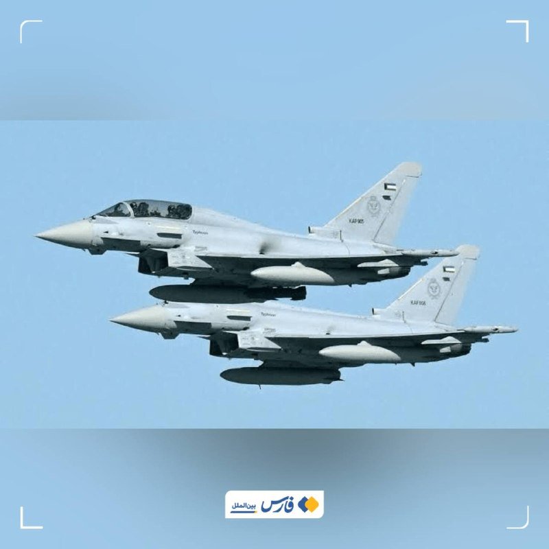 Two gray fighter jets fly in close formation against a clear blue sky, each carrying external fuel tanks.