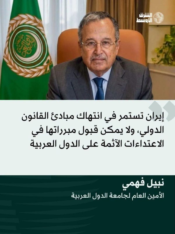 A man in a suit and tie sits in an office chair with the Arab League flag beside him, with Arabic text displayed below.
