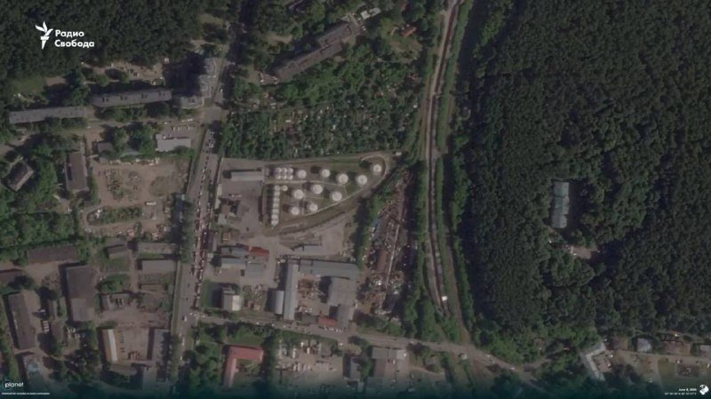 Satellite image shows an industrial facility with cylindrical storage tanks, adjacent railway tracks, surrounding forest, and a "Радио Свобода" logo in the upper corner.