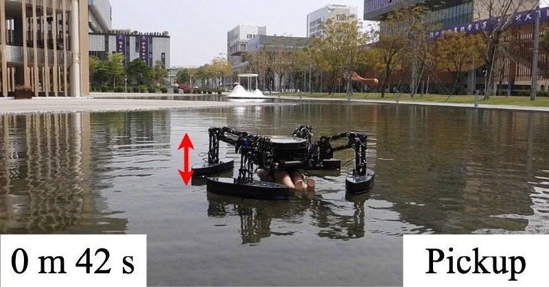 A multi-rotor water drone floats on a shallow urban pond, its labeled black arms holding a brown object during a "Pickup" action at 0m 42s.