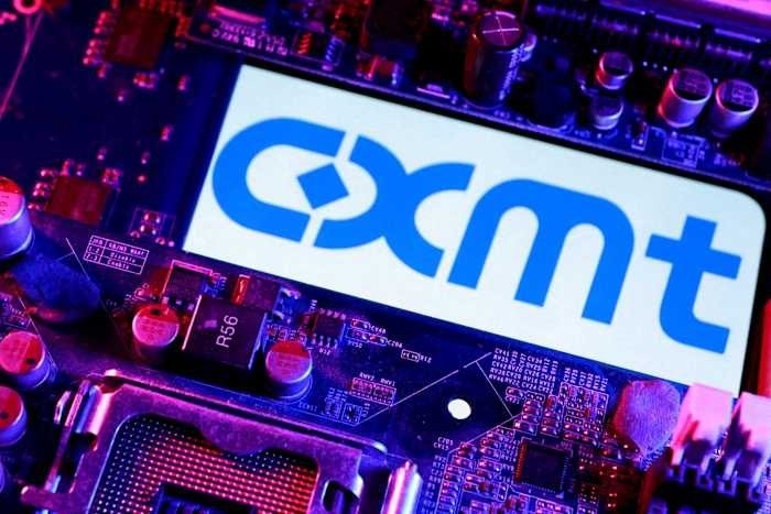 An illuminated screen displays the blue text "CXMT" against a backdrop of a purple-lit computer motherboard with visible circuitry and electronic components.
