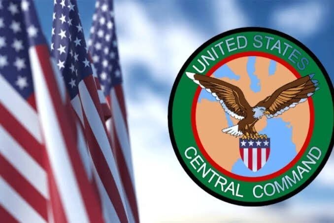 American flags wave in the foreground alongside the United States Central Command emblem, which features a bald eagle holding a shield against a green border.