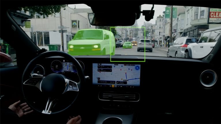 Interior view of a vehicle shows a highlighted green van ahead on a city street, with a navigation screen and steering wheel visible in the dashboard.