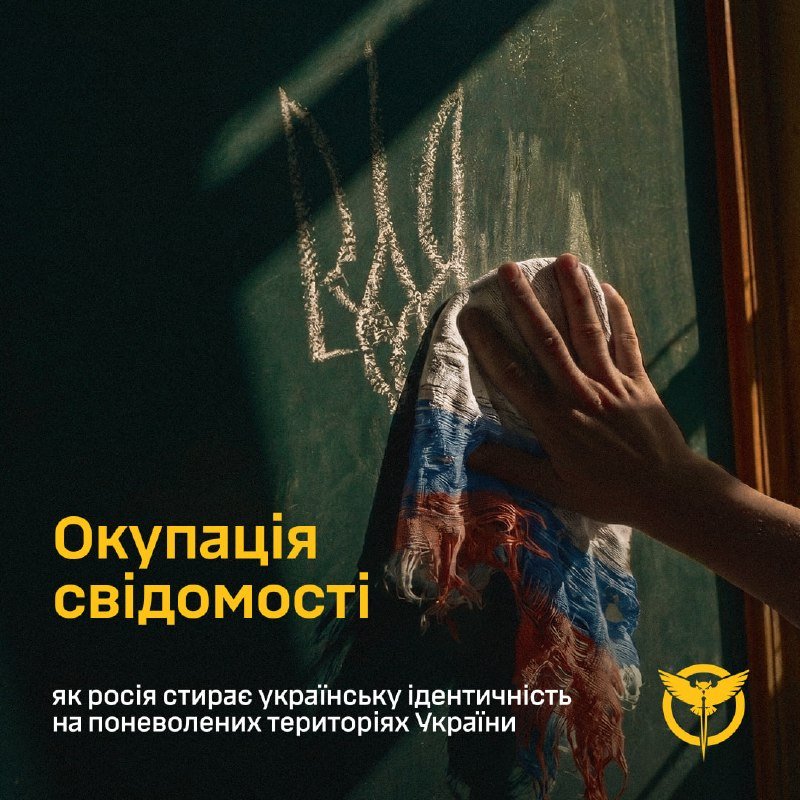 A hand wipes away a Ukrainian flag motif drawn on a chalkboard with a cloth, accompanied by Ukrainian text reading "Окупація свідомості."
