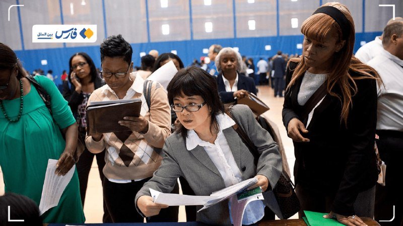 Attendees in business attire hold documents and folders while gathered at a job fair in a large hall.