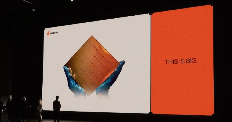 A large presentation screen displays the Cerebras logo, an image of gloved hands holding a chip, and the text "THIS IS BIG." silhouetted figures stand in the foreground.