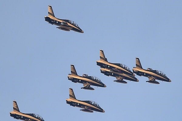 Six military jet aircraft fly in a tight formation against a clear blue sky.