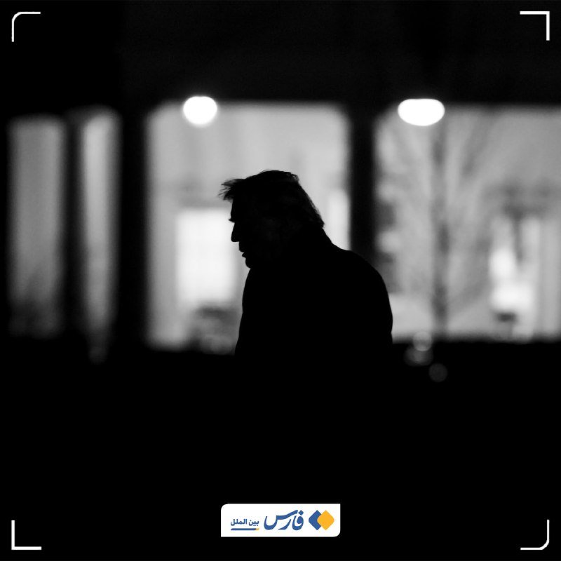 A silhouetted figure of a person is shown in profile against a blurred background of illuminated interior windows in this black-and-white photograph.