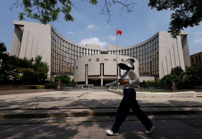 A pedestrian walks past a quotation board displaying Chinese and US Treasury yields outside a brokerage in Shanghai.