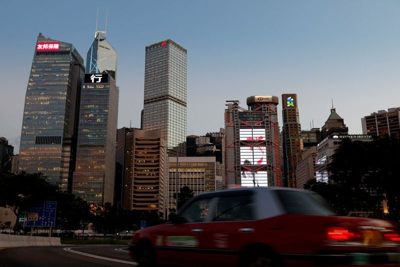 Pedestrians in Shanghai walk past an exchange display showing Chinese equity indices.
