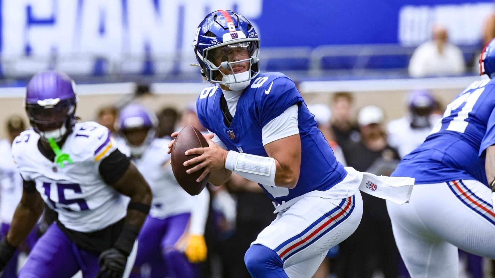 A quarterback in a blue jersey with the number 8 looks to pass during an NFL game between the New York Giants and Minnesota Vikings.