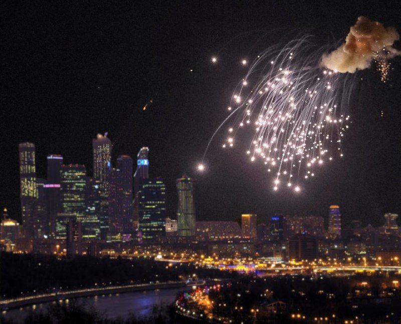 Fireworks explode over a brightly lit city skyline at night, with illuminated skyscrapers and a riverfront visible below.