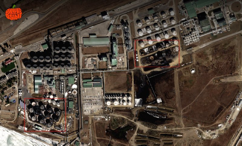 Aerial satellite image showing an industrial facility with numerous circular storage tanks, rectangular buildings, and two areas outlined in red.