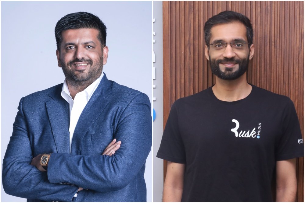 A split image showing two smiling men posing for portraits: one in a blue blazer against a light background, the other wearing glasses and a black "Rusk Media" t-shirt against a wooden backdrop.