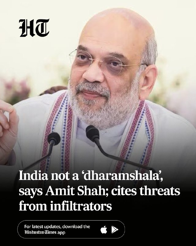 A bald, bearded man in a white patterned shawl speaks at microphones, with an "HT" logo and a news headline beneath reading "India not a 'dharamshala', says Amit Shah; cites threats from infiltrators."