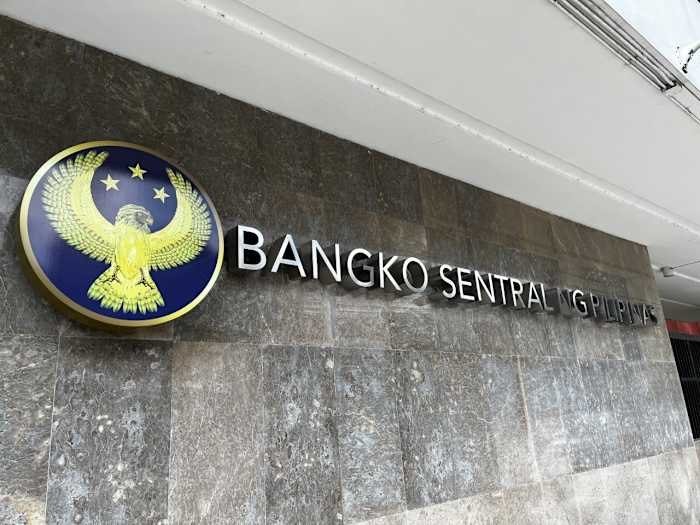 A circular emblem featuring a golden eagle and stars beside the text "BANGKO SENTRAL NG PILIPINAS" is mounted on a gray stone wall.