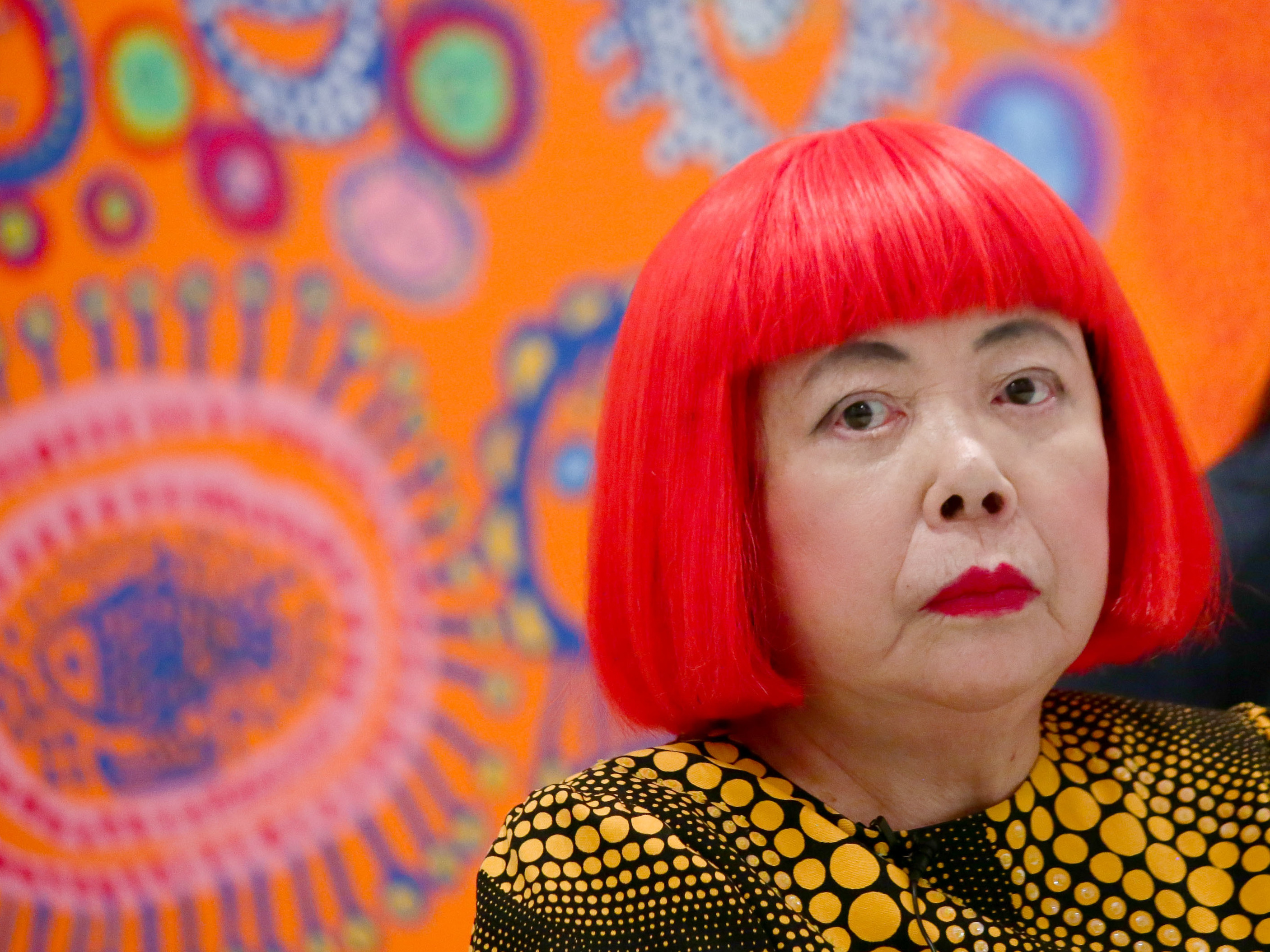 Yayoi Kusama in front of one of her signature polka-dotted works, the visual vocabulary she refined across more than seven decades.